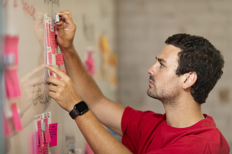 Man putting notes on a white board.