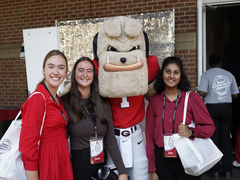 Three students participating in the Student Leadership Conference take a photo with Hairy Dawg.
